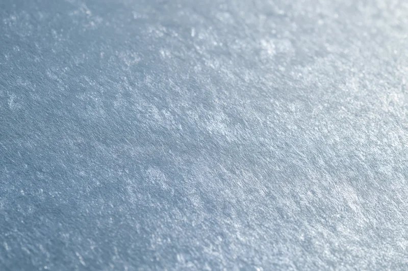 Close-up of frosted glass surface with brushed metallic texture and soft light reflections