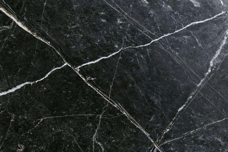 Close-up of polished black marble surface with white veining and natural cracks