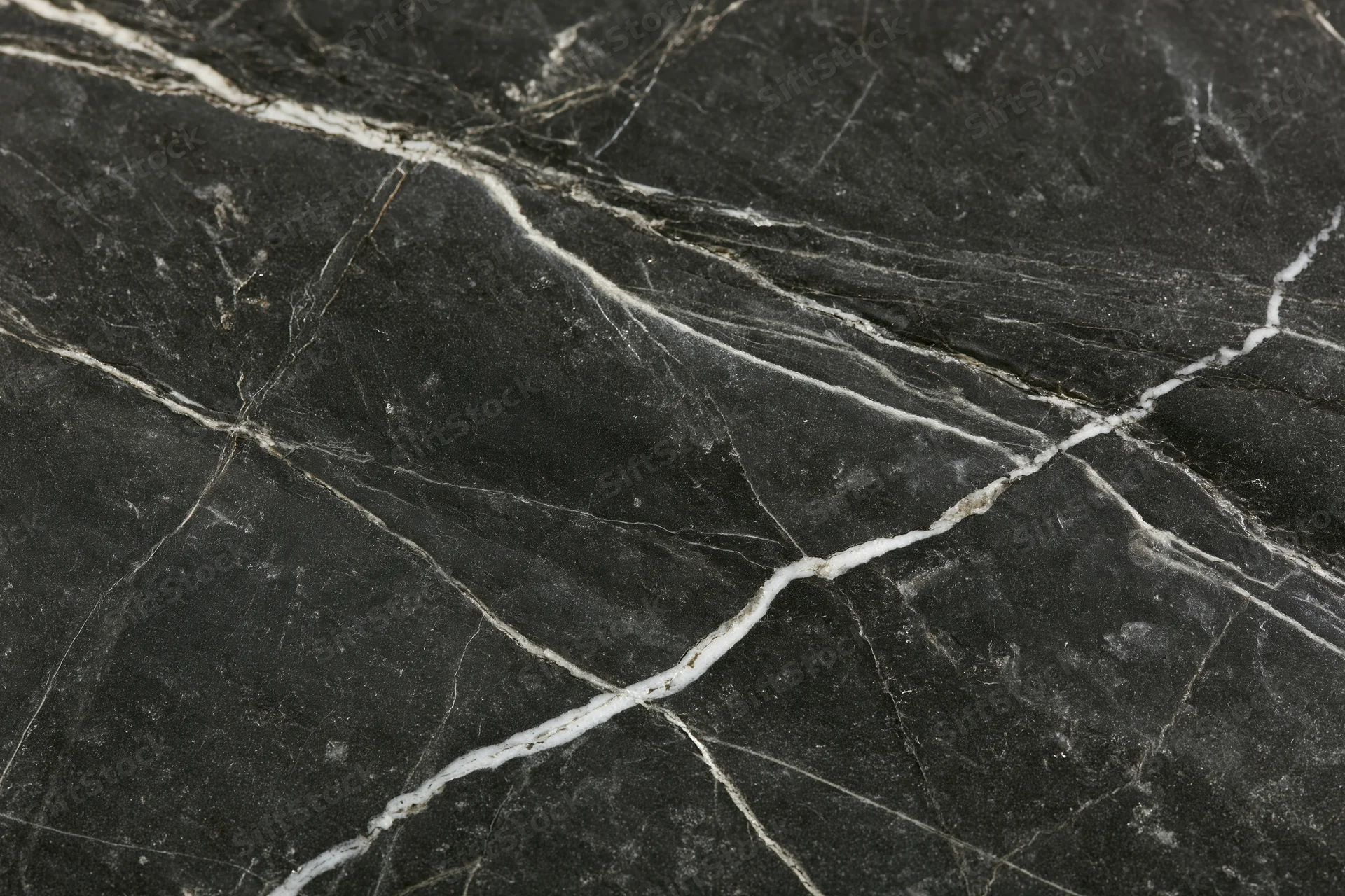 Close-up of polished black marble surface with white veining filling the frame