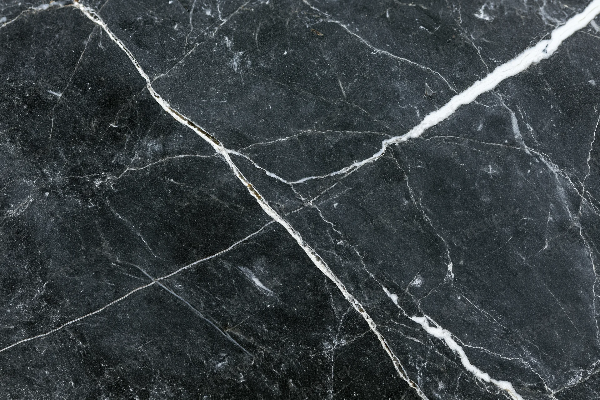 Close-up of polished black marble surface with white veining filling the frame