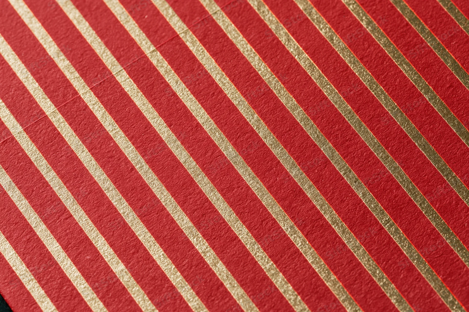 Close-up of red wrapping paper with diagonal gold stripes for holiday gift wrapping