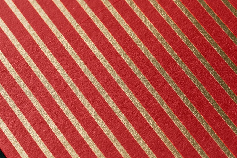 Close-up of red wrapping paper with diagonal gold stripes for holiday gift wrapping