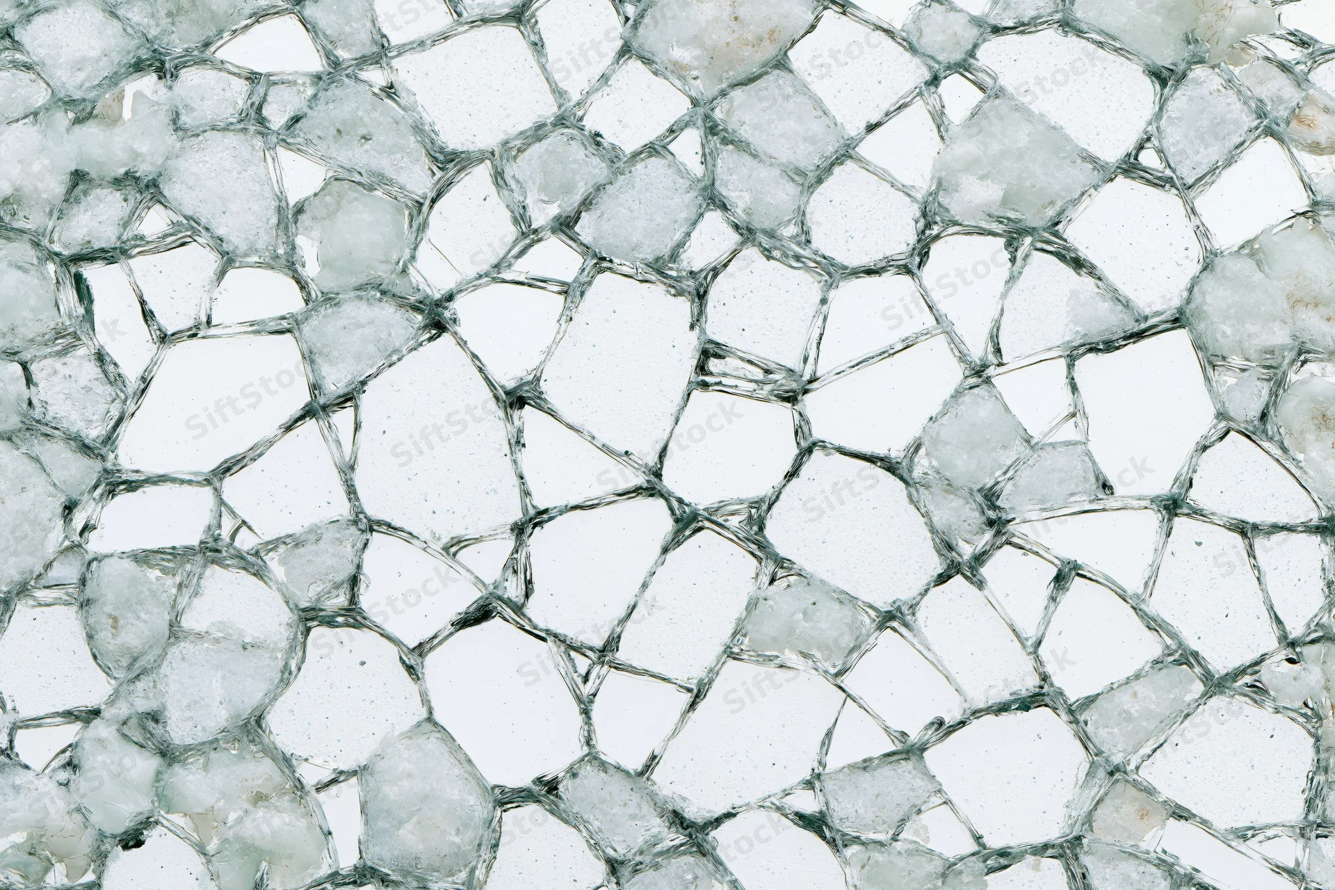 Close-up of shattered glass fragments forming a dense web-like pattern on a flat surface