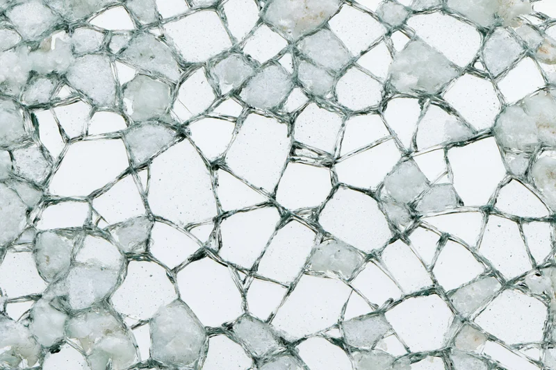 Close-up of shattered glass fragments forming a dense web-like pattern on a flat surface