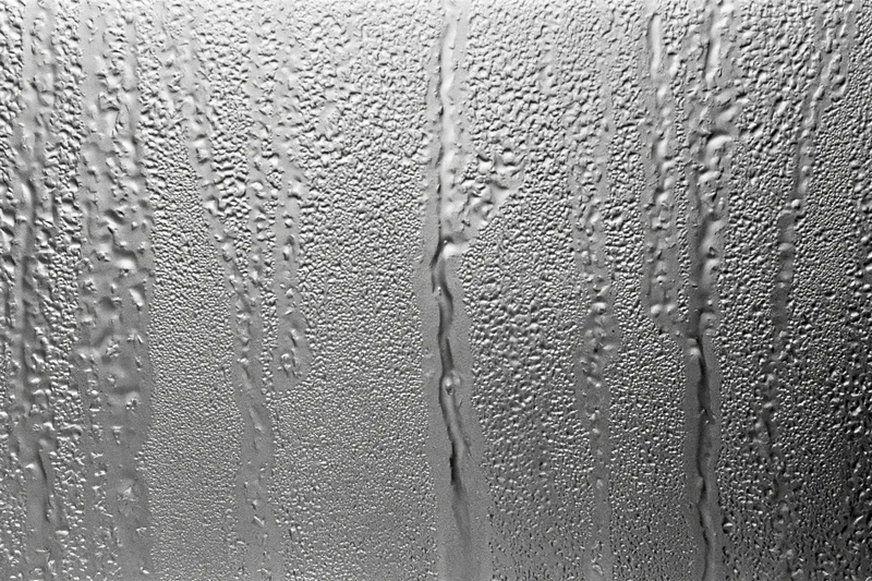 Close-up of water droplets and streaks on a fogged glass window surface