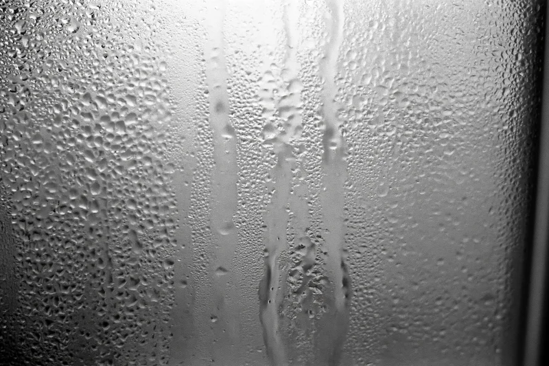 Close-up of condensation droplets and streaks on a fogged window glass surface