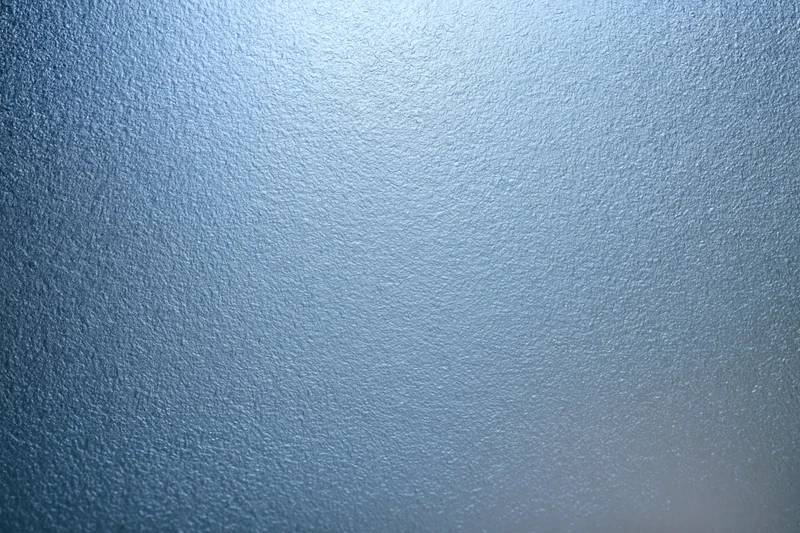 Close-up of frosted glass surface with fine uniform texture and blue gradient lighting