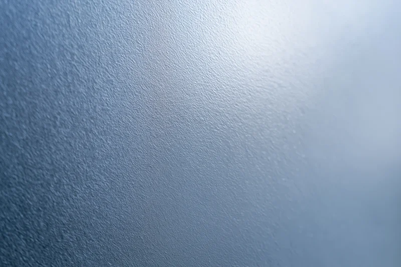 Close-up of frosted glass surface with fine texture and blue gradient lighting