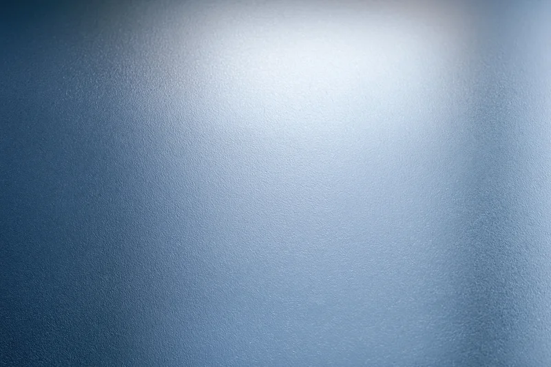 Close-up of frosted glass surface with smooth texture and blue gradient lighting
