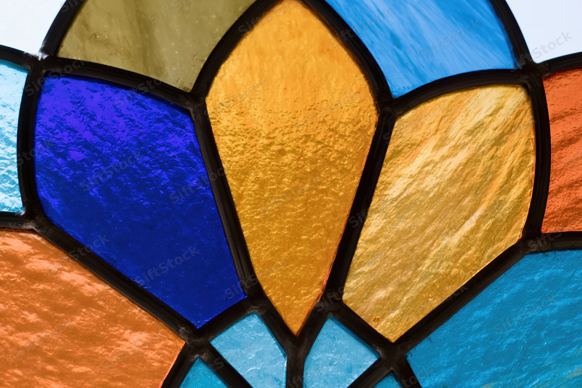 Close-up of a stained glass window with radial geometric pattern and colorful translucent glass panels