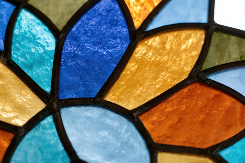 Close-up of a stained glass window with a radial geometric pattern in vibrant colors