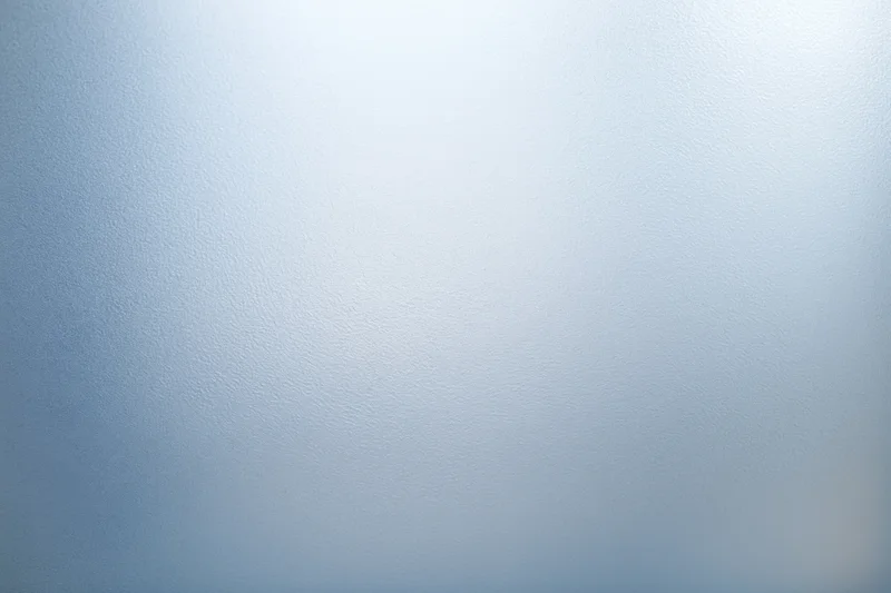 Frosted glass surface with smooth texture and soft light gradient filling the frame