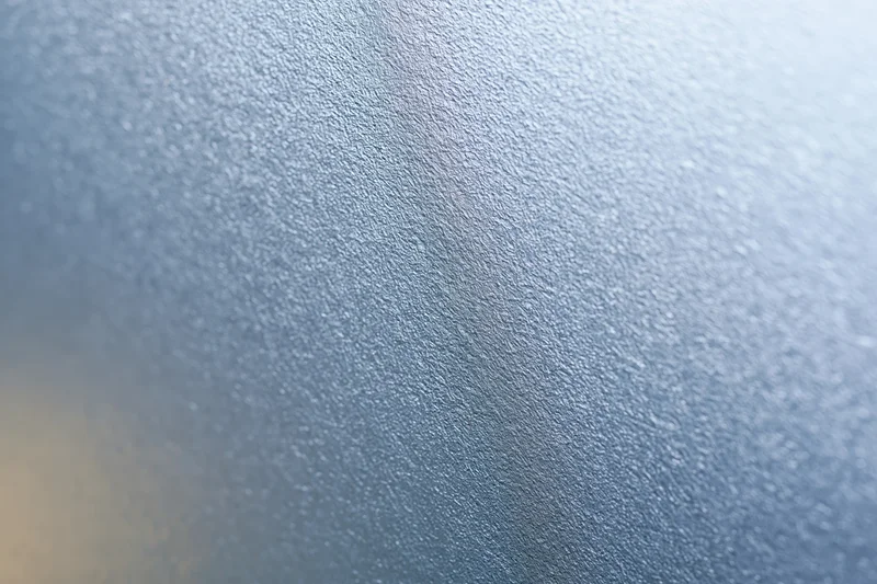 Close-up of frosted glass surface with textured pattern and soft light gradient