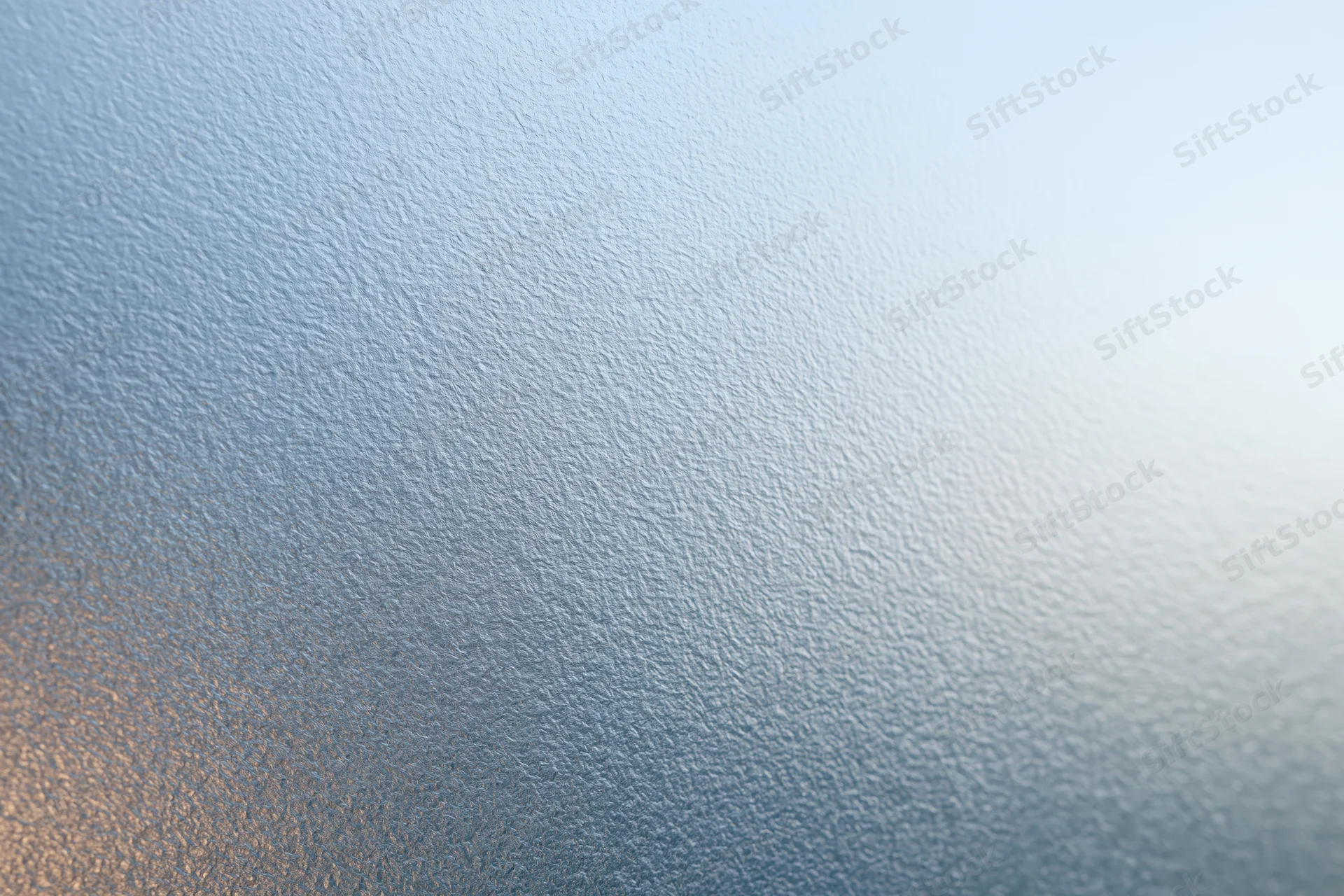 Close-up of frosted glass surface with textured pattern and light gradient
