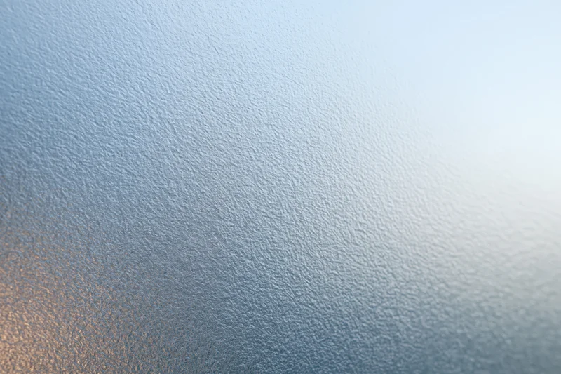 Close-up of frosted glass surface with textured pattern and light gradient