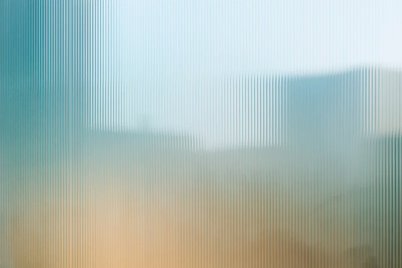 Close-up of ribbed translucent glass panel with vertical lines and soft color gradient