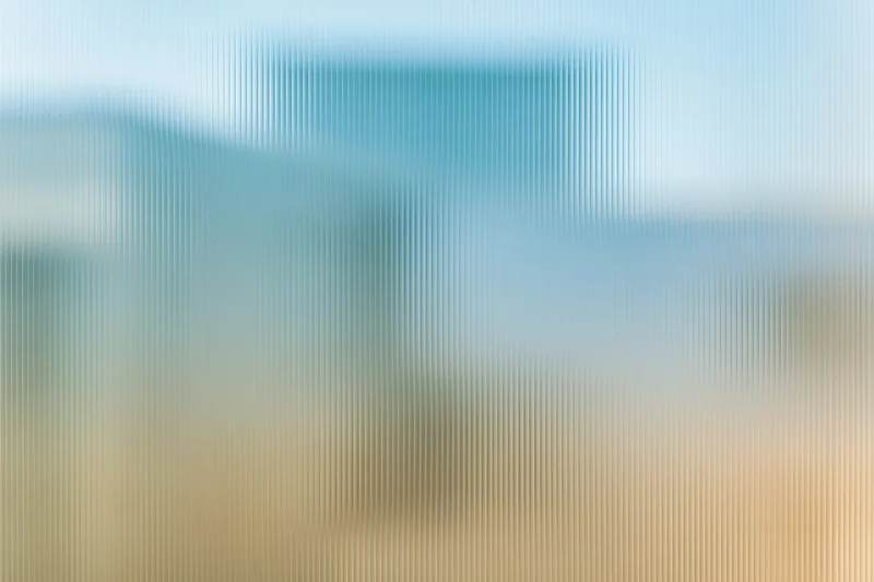 Close-up of ribbed translucent glass panel with vertical lines and soft blue-beige gradient