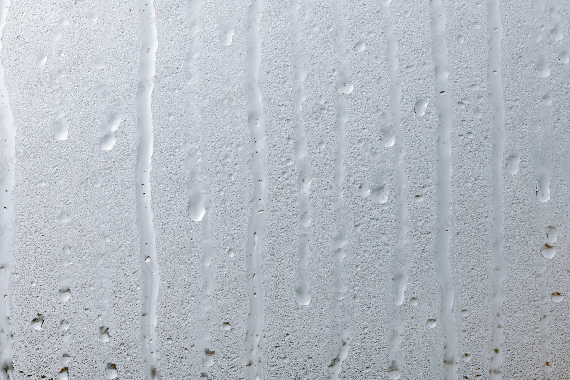 Close-up of water droplets and streaks on a wet glass surface