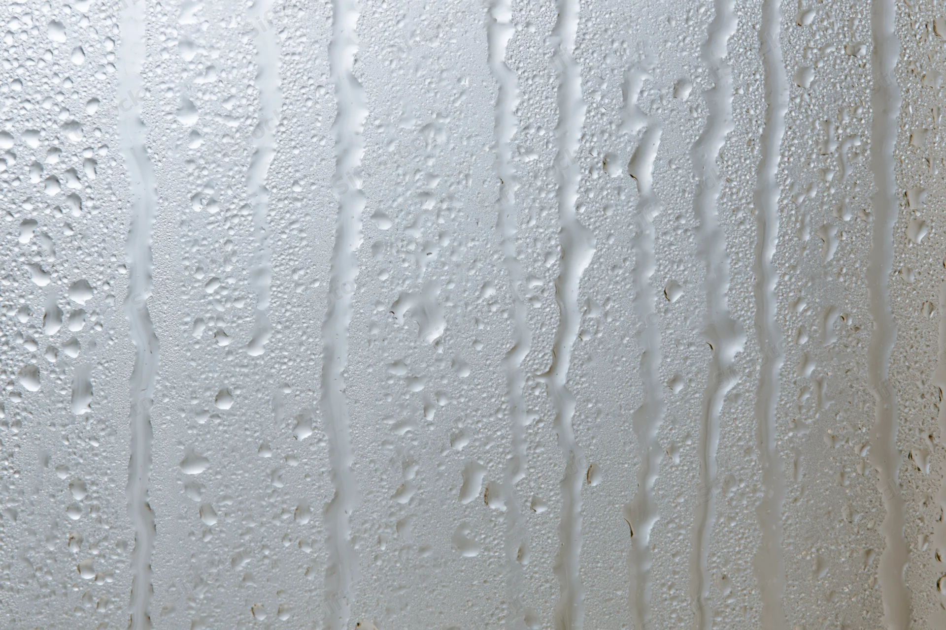 Close-up of water droplets and streaks on a wet glass surface