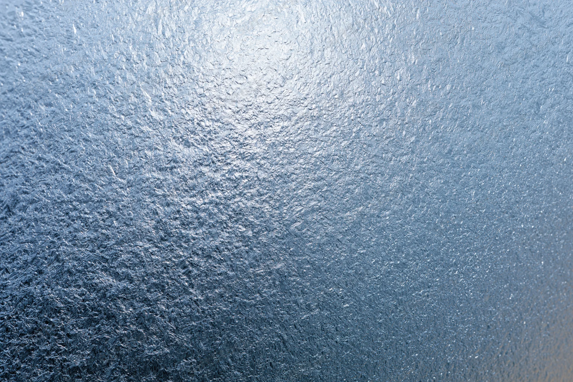 Close-up of frosted glass surface with icy texture and blue gradient