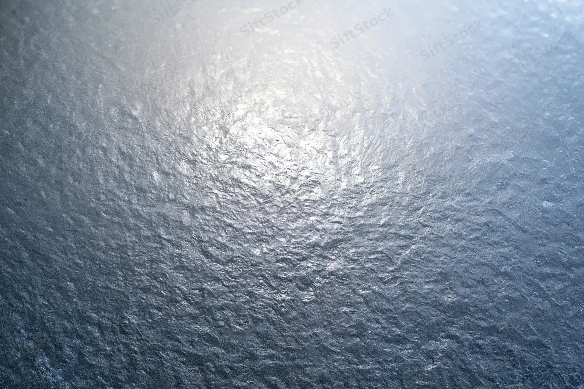 Close-up of frosted glass surface with icy texture and light reflection