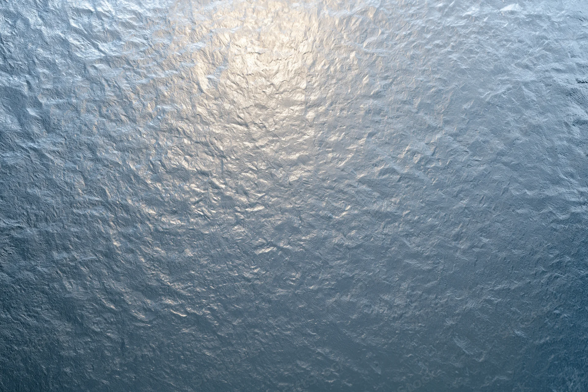 Close-up of frosted glass surface with light reflection and icy texture