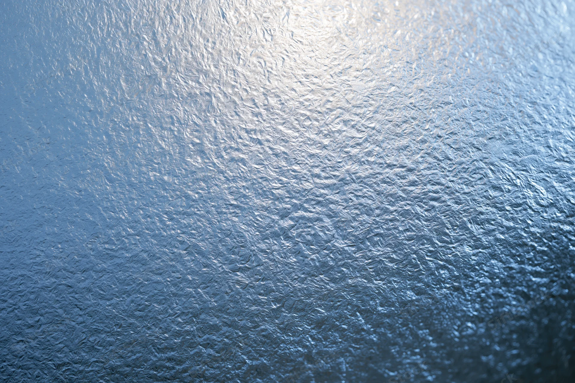 Close-up of frosted glass surface with icy texture and light reflection