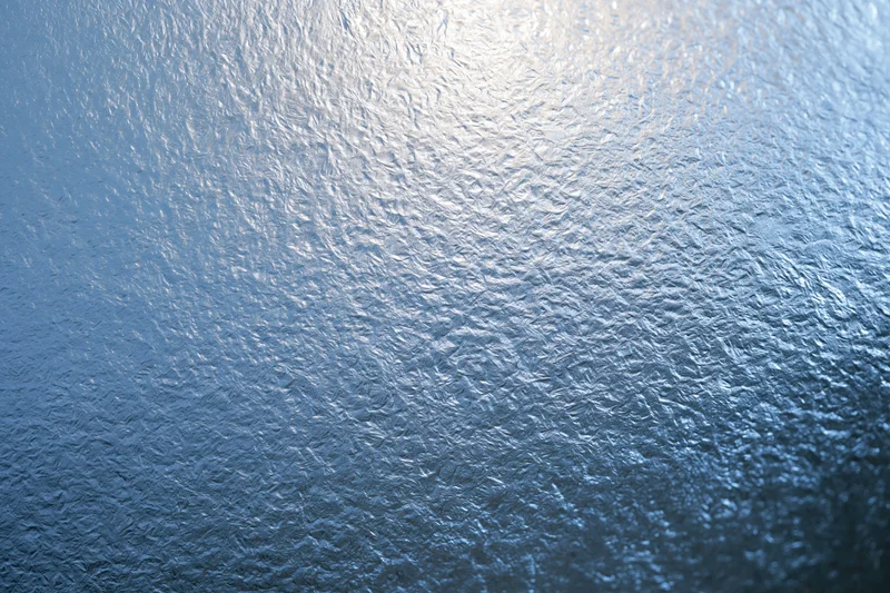 Close-up of frosted glass surface with icy texture and light reflection