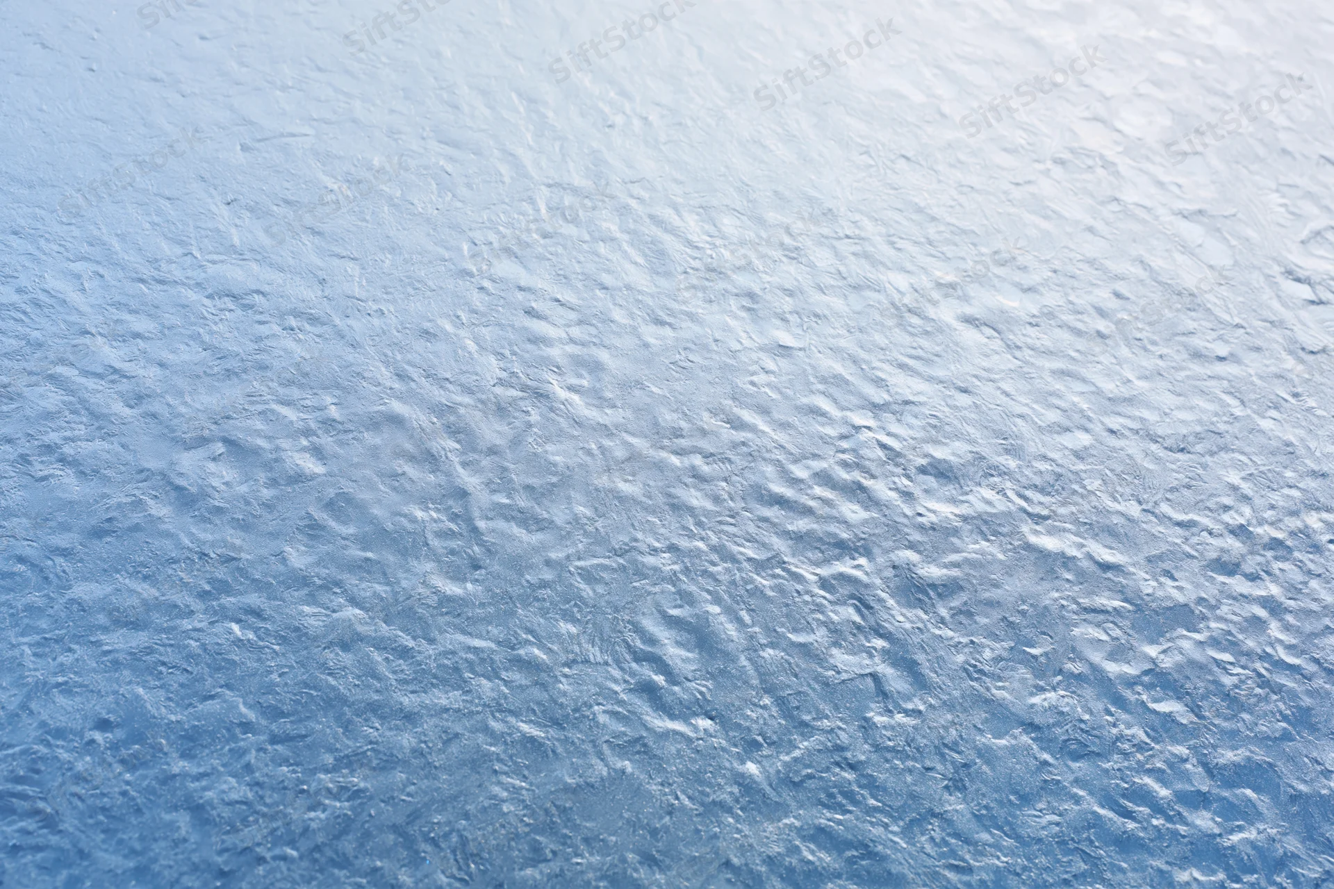 Close-up of frosted glass surface with icy texture and blue-white gradient