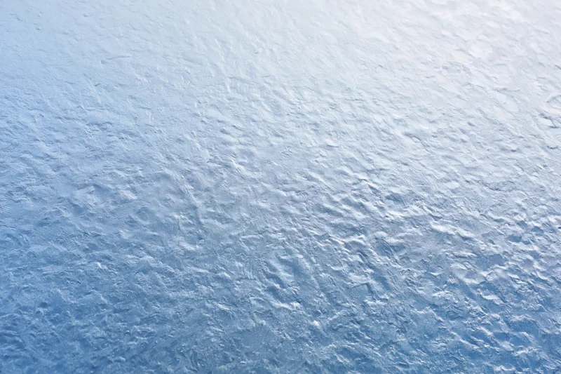 Close-up of frosted glass surface with icy texture and blue-white gradient