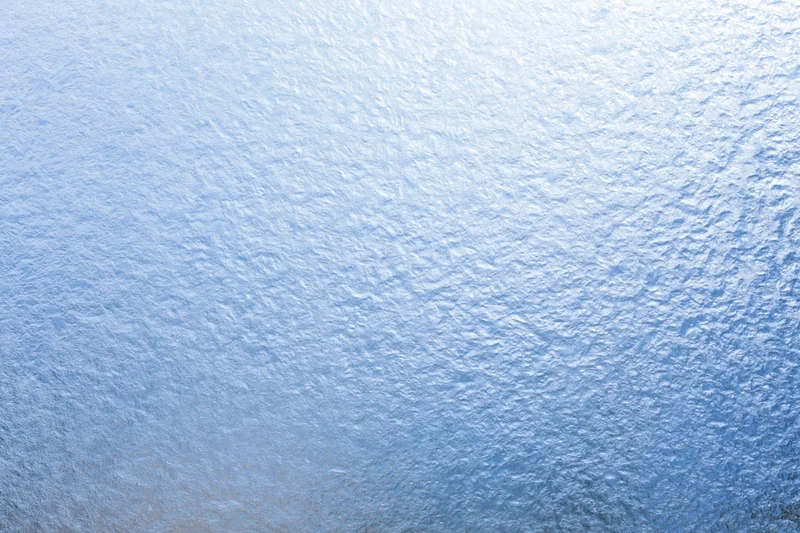 Close-up of frosted glass surface with icy texture and blue light gradient