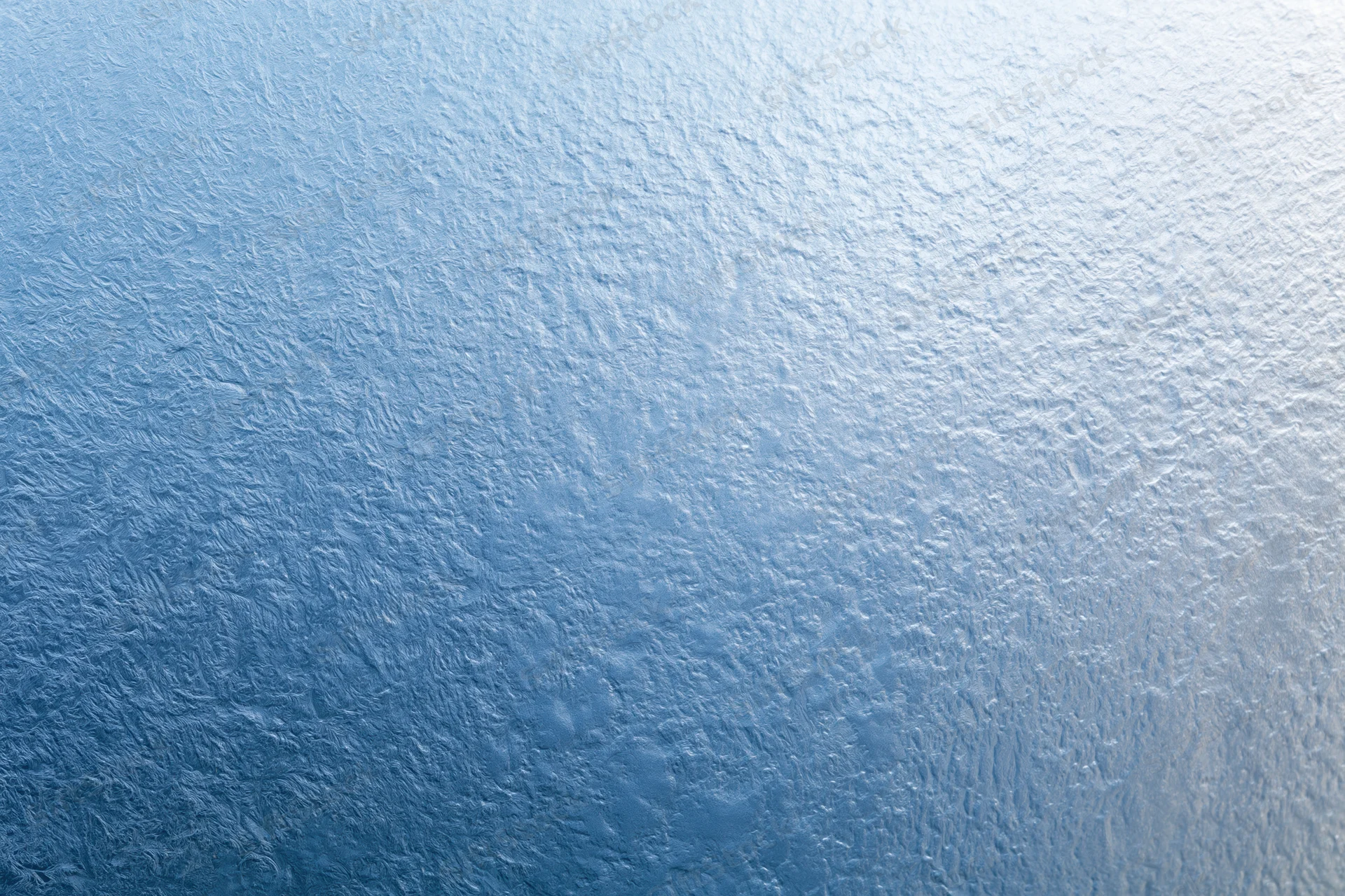 Close-up of frosted glass surface with icy texture and blue gradient