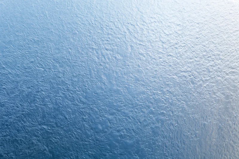 Close-up of frosted glass surface with icy texture and blue gradient
