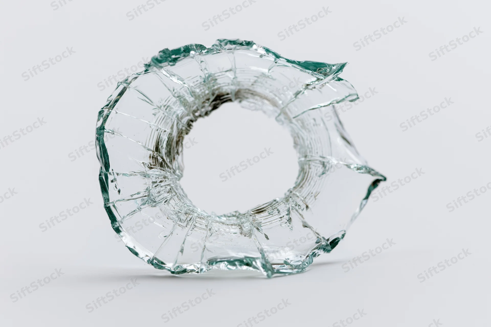 Shattered glass with circular bullet hole on white background