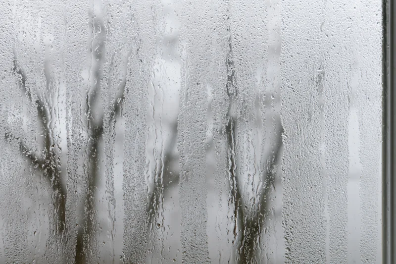 Fogged window pane covered in condensation with water droplets and streaks