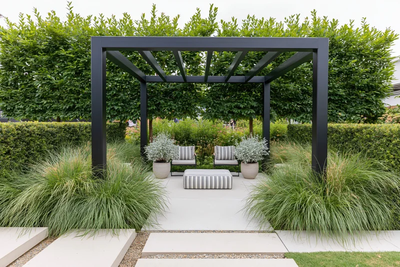 Black steel pergola with striped seating and potted plants in a contemporary garden setting