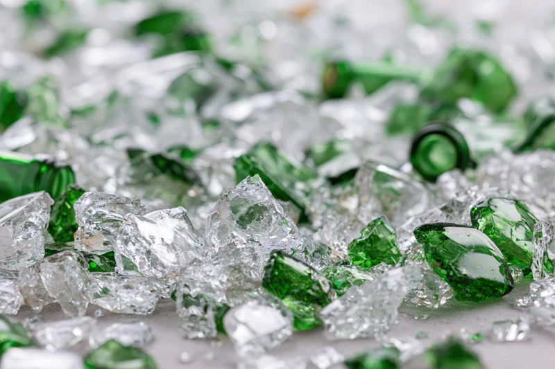 Broken green glass bottle shards scattered densely on a surface