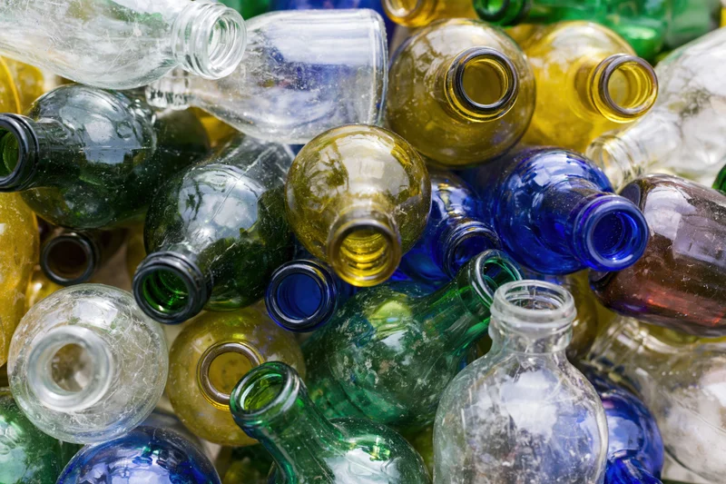 Pile of empty glass bottles in various colors and shapes