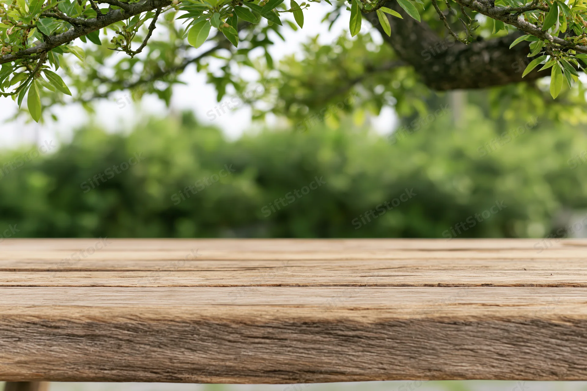 Weathered wooden table surface in a lush green garden setting