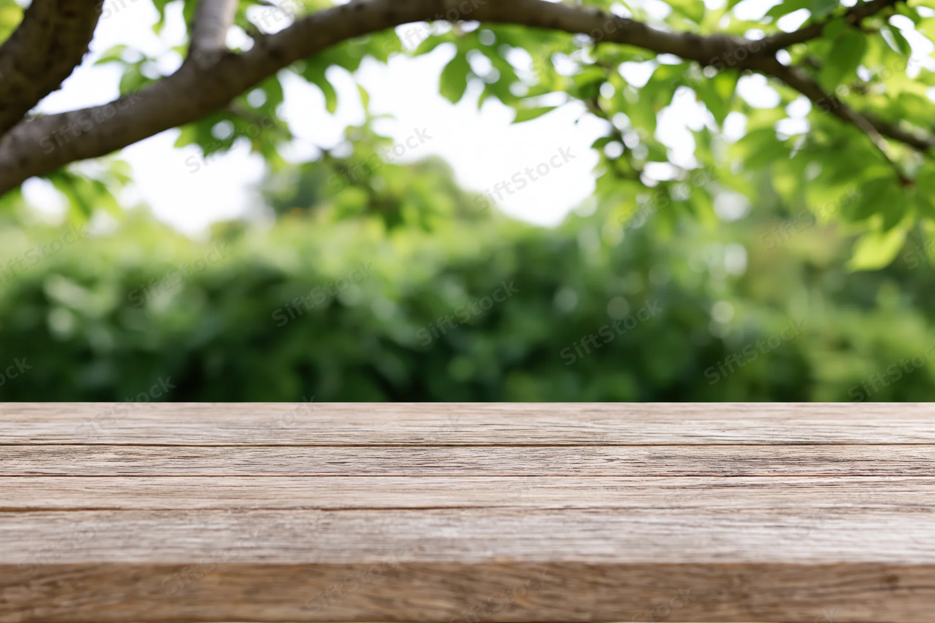 Weathered wooden table surface in front of blurred green foliage outdoors