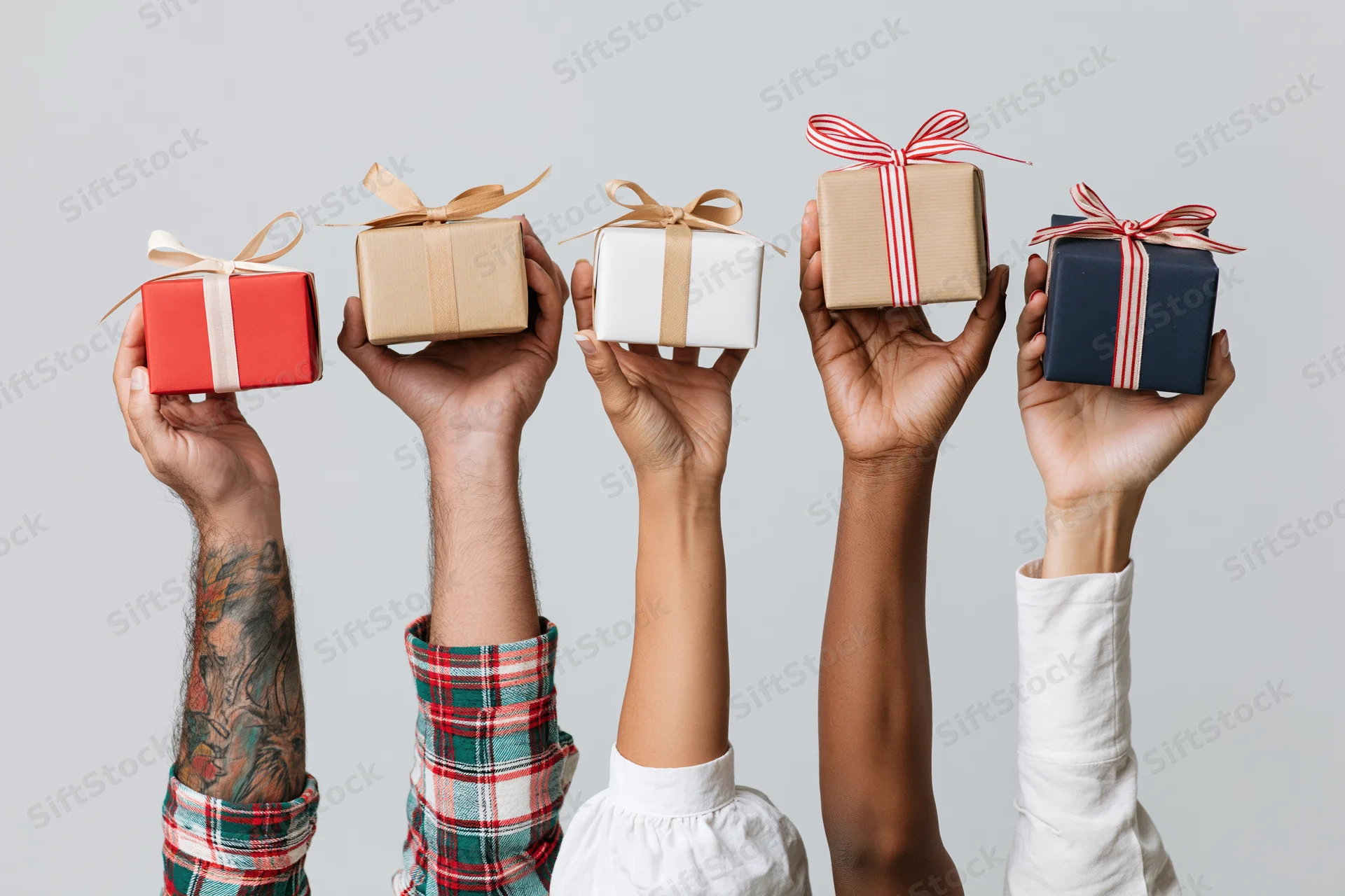 Five diverse hands holding wrapped gifts raised upward against a plain background