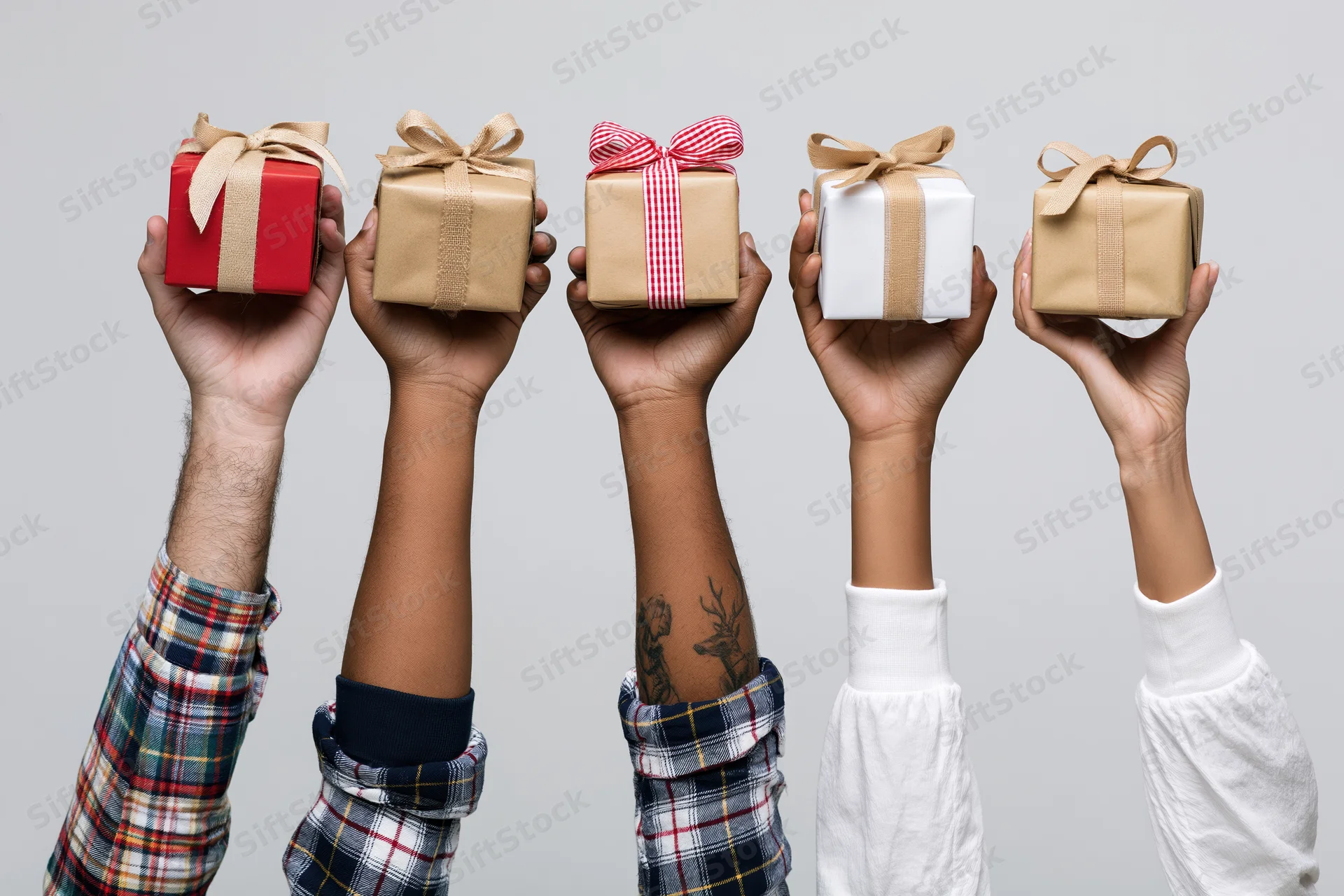 Five diverse hands holding wrapped gifts upward against a plain background