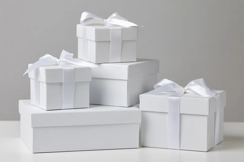 White gift boxes stacked and arranged on a plain surface with ribbons and bows