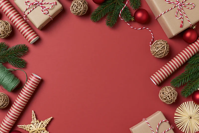 Christmas gift wrapping supplies arranged in a flat lay on red background with copyspace