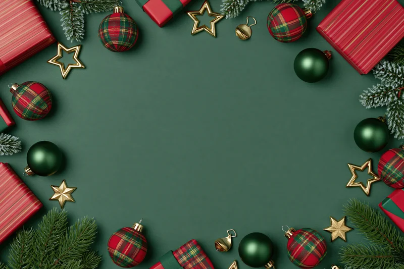 Christmas ornaments and wrapped gifts arranged in a flat lay around a green background with copyspace