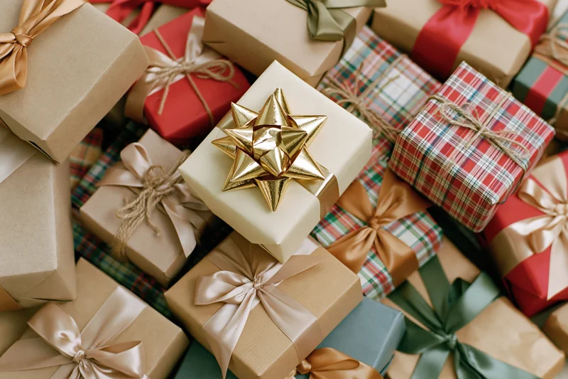 Pile of wrapped christmas gifts in various papers and ribbons filling the frame