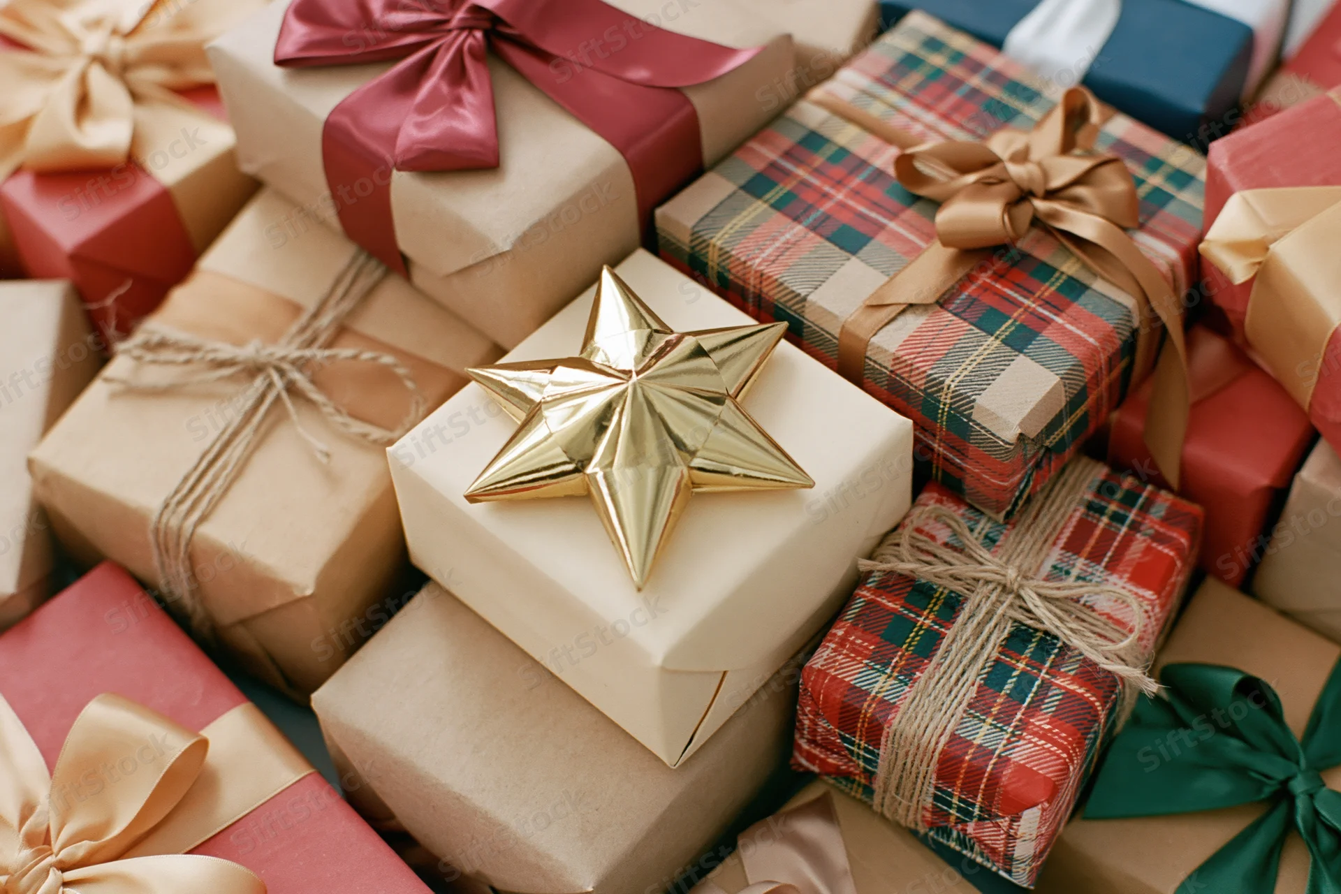 Pile of wrapped christmas gifts in various papers and ribbons, overhead view