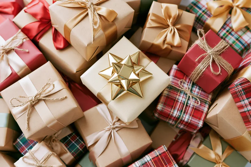 Pile of wrapped christmas gifts in various papers and ribbons filling the frame