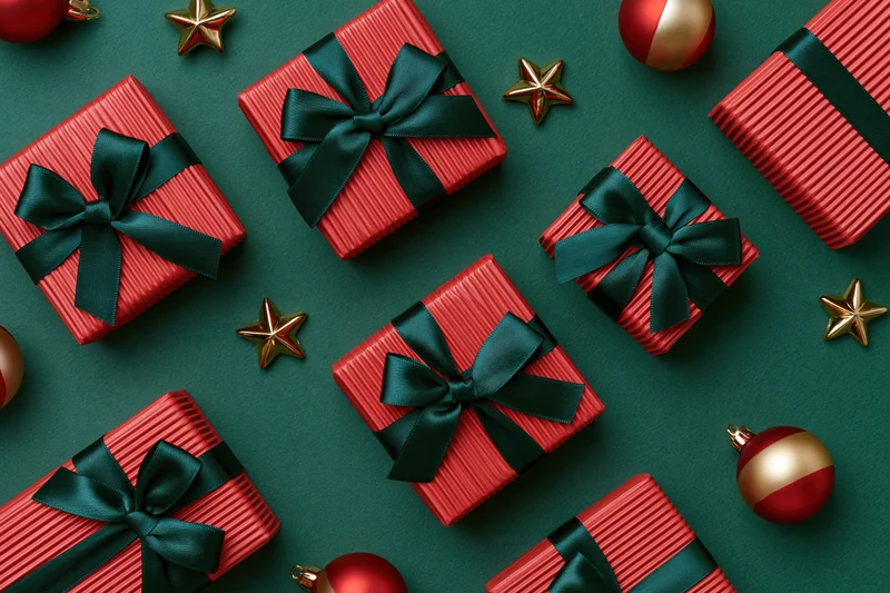 Red striped gift boxes with dark green satin bows and gold stars on green background