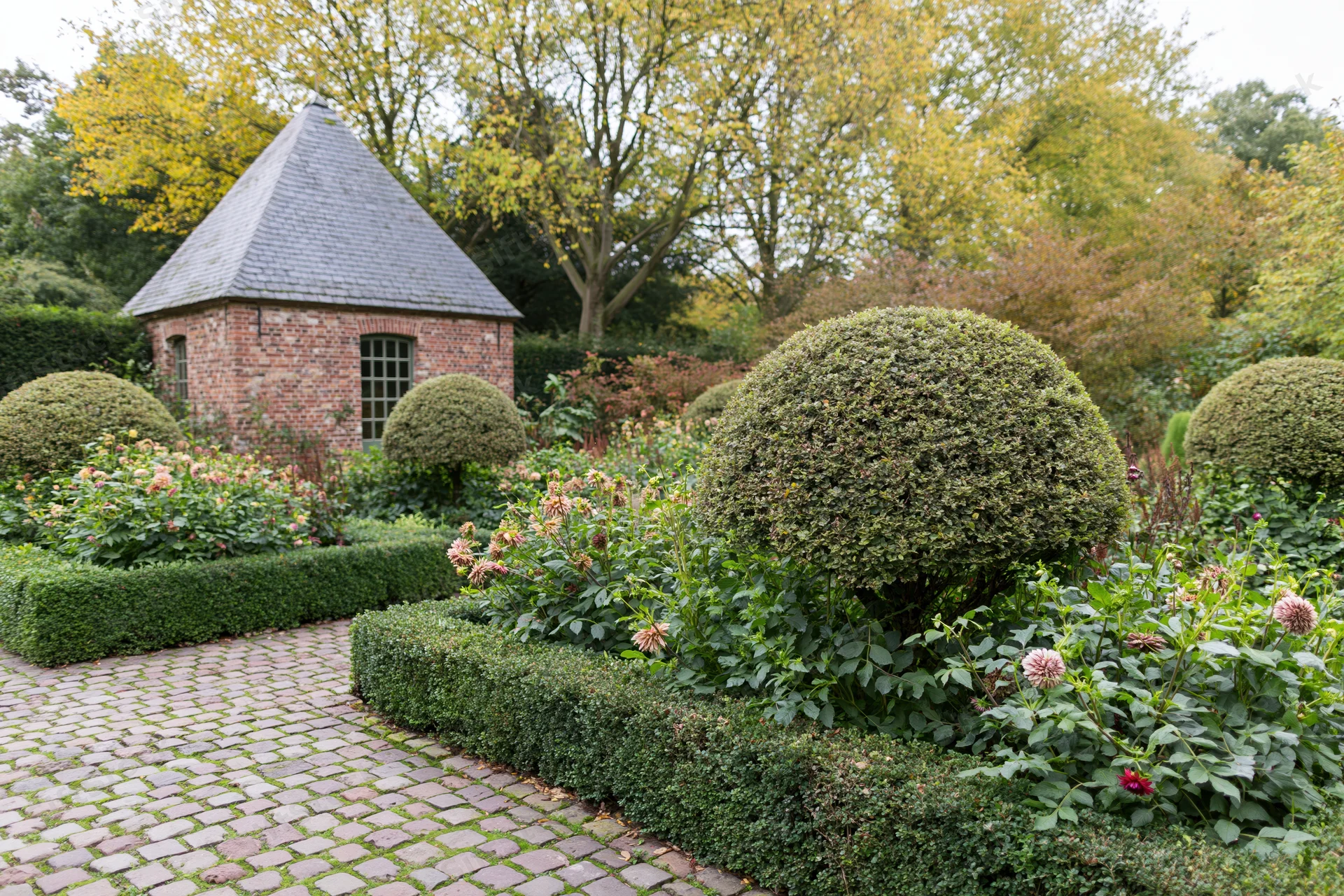 Formal european garden with brick gazebo and topiary hedges in early autumn